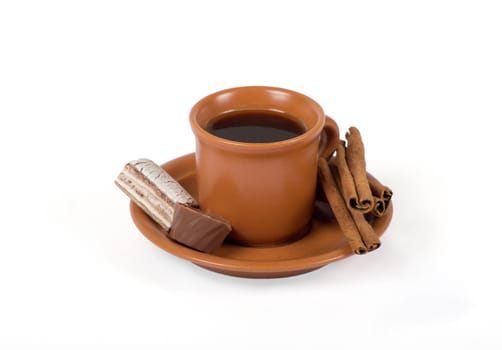Closeup shot of freshly prepared cup of italian espresso with cinnamon and candy over white background