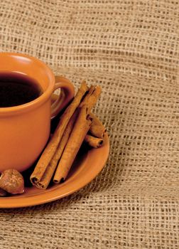 Closeup shot of freshly prepared cup of italian espresso with cinnamon, coffe beans, nuts and lemon over sacking