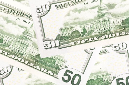 A stack of fifty 50 dollar bills fanned out with the back US Capitol showing on a white background