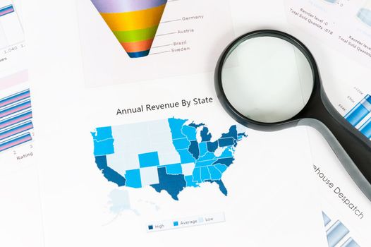 Business graph printed on the white paper with a magnifier on it