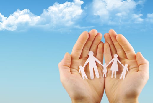 Paper family in hands isolated on blue sky
