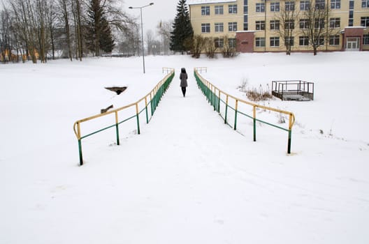 woman in grey coat walk through frozen river bridge in winter and snowstorm snow fall.