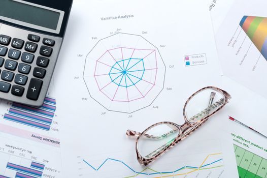 Business graph printed on white paper with calculator and glasses