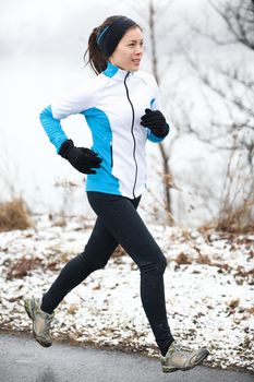 Fit slender young woman taking her daily exercise out jogging in a snowy landscape in winter