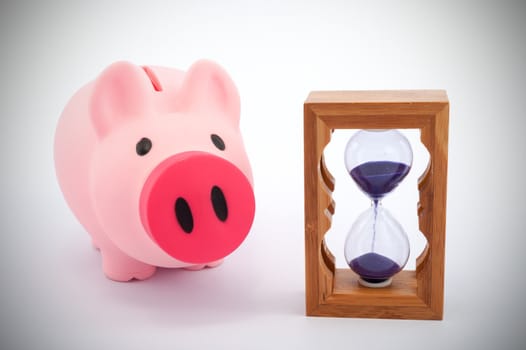 Piggy bank and hourglass objects on white background