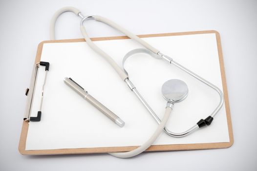 Stethoscope and clip board with blank paper on a white background.