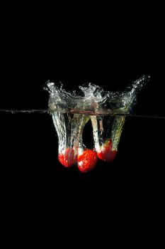 Colored red paprika in water splashes on black background