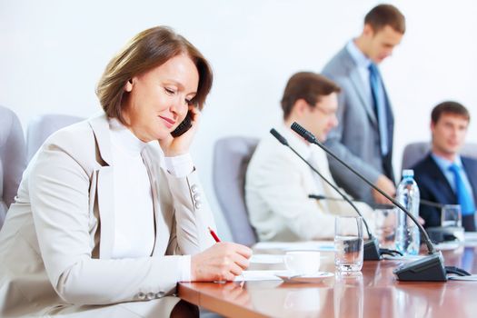 Image of businesswoman at business meeting with three businessmen in background