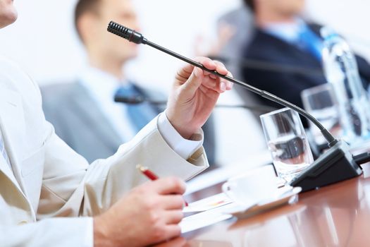 Image of businessman's hands holding microphone at conference