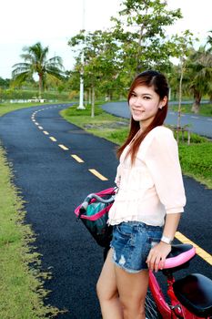 asian women and bicycle on the road at the park