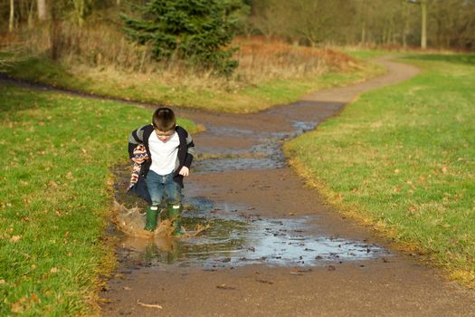 little boy splashing in a puddle