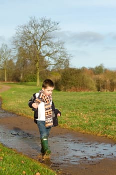 little boy splashing in a puddle