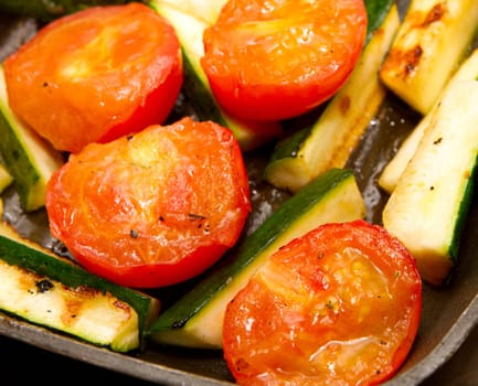 Corgettes and tomatoes frying in a griddle pan