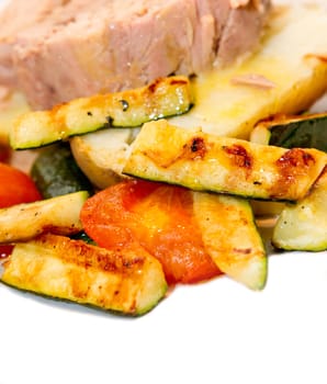 Corgettes and tomatoes frying in a griddle pan