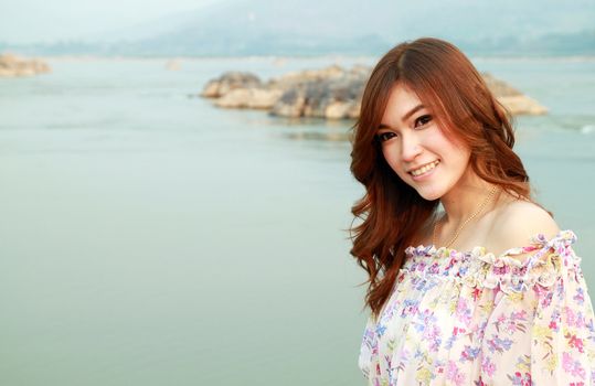 a portrait of beautiful woman with river background