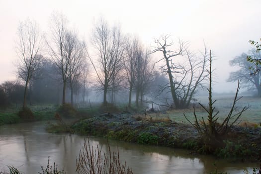 Misty river running through misty fields