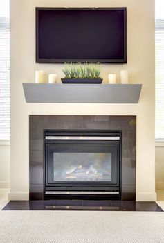 Modern new fireplace with large TV and shelve with candles.