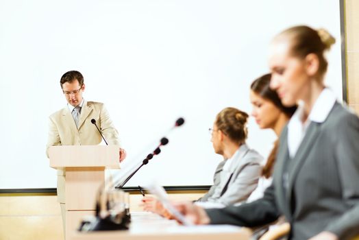 businessmen talking at the conference, sitting at the table, on the table microphones and documemts