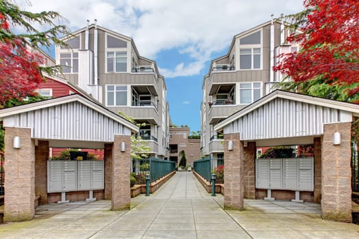 Modern apartment buildiing with mail boxes and red maple.