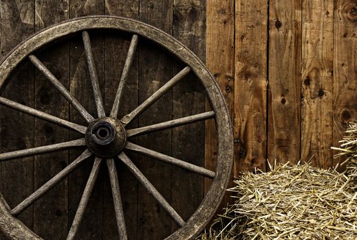 Vintage wooden carriage wheel, straw and wood background