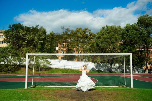 Beautiful bride on the football field in the gate