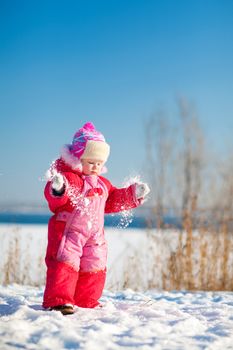 small child throwing snow in winter