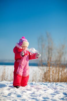 small child throwing snow in winter