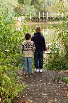 Brothers looking out across a pond in Autumn