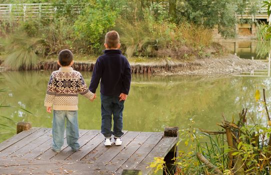 Brothers looking out across a pond in Autumn