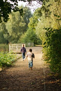 Brothers running near a pond in Autumn