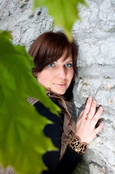 Beautiful blue-eyed smiling girl outdoors near the wall and maple