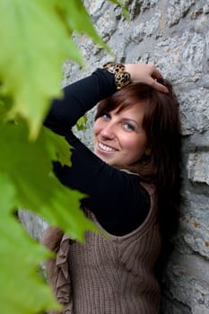 Beautiful blue-eyed smiling girl outdoors near the wall and maple