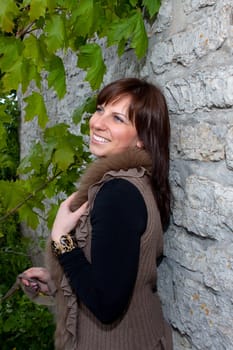 Beautiful blue-eyed smiling girl outdoors near the wall and maple