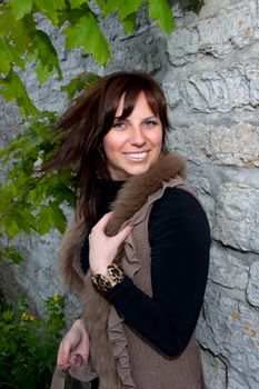 Beautiful blue-eyed smiling girl outdoors near the wall and maple