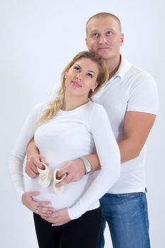 Happy prospective parents with self-made child's boots embrace smiling. 