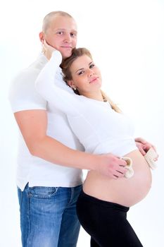 Happy prospective parents with self-made child's boots embrace smiling. 