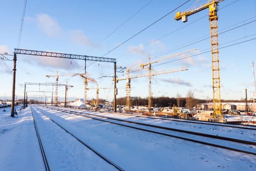 Huge industrial cranes on the construction site near rail road - winter season