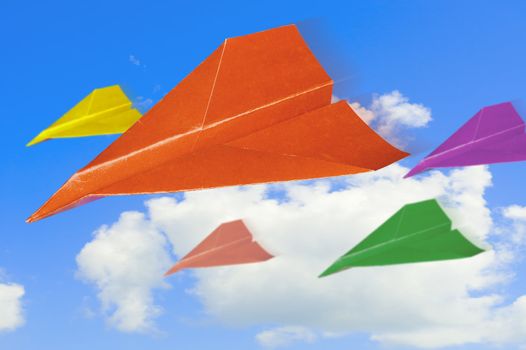 Colored  paper planes against sky with clouds.