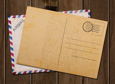 Old blank post card and envelope, on wooden table.