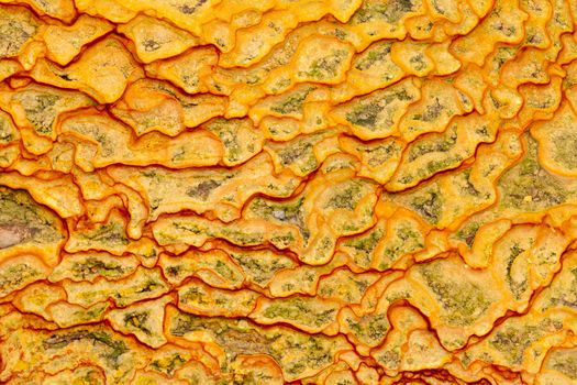 Background texture pattern of natural iron oxide rich yellow-orange mineral sediment deposit from water