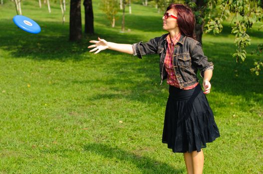 Young woman having fun with frisbee in the parkin sunny summer day.