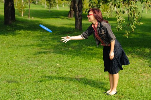 Young woman having fun with frisbee in the parkin sunny summer day.