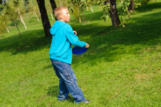 Little boy playing frisbee on green grass