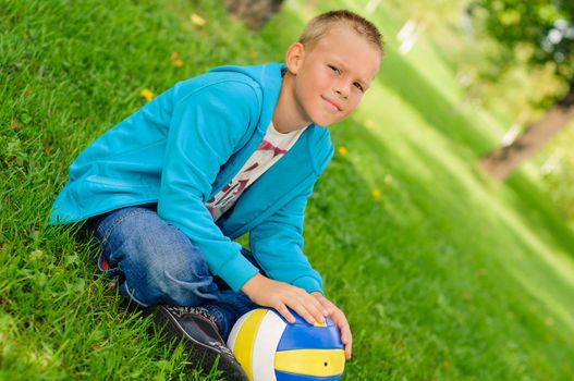 Young boy in jeans sitting on the grass