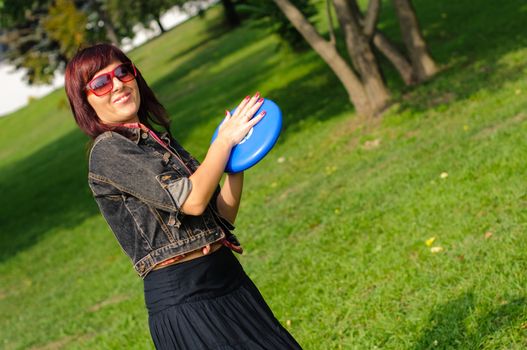 Young woman having fun with frisbee in the parkin sunny summer day.