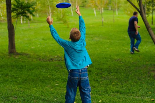 Little boy playing frisbee on green grass