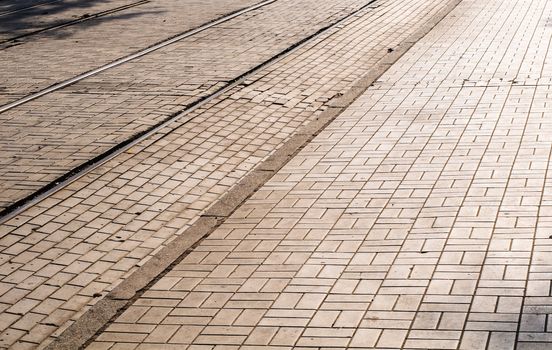 Cobblestone road in the sunlight with tram's rails