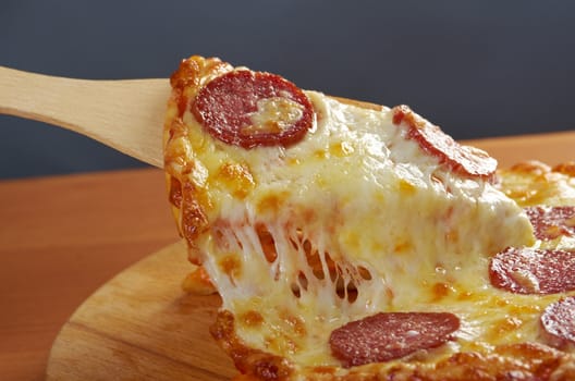 homemade pizza  Pepperoni .taking slice of pizza,melted cheese dripping.