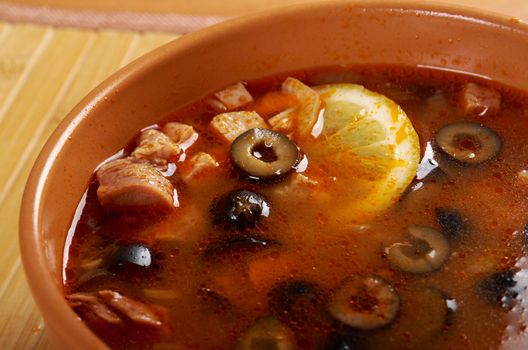 Solyanka on the plate.Solyanka, Russian soup with beef,sausage,chicken and lemon, olives