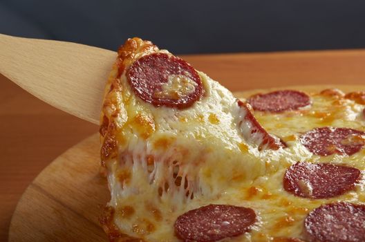 homemade pizza  Pepperoni .taking slice of pizza,melted cheese dripping.